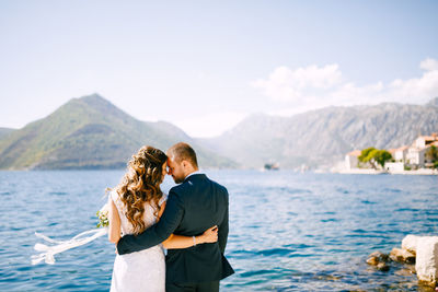 Rear view of couple standing on mountain against sky