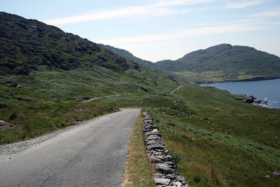 Road leading towards mountains against sky