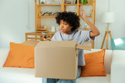 Young woman using digital tablet while sitting on sofa at home