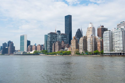 River by modern buildings against sky in city