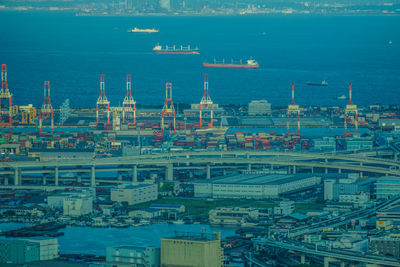 High angle view of illuminated city by sea against sky