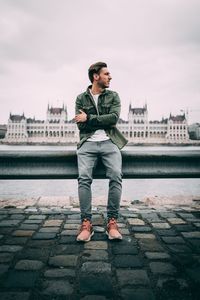 Full length of man sitting on railing in city