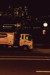 Cars on street against illuminated buildings in city at night