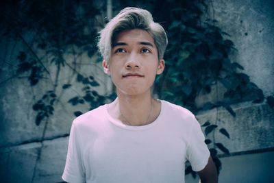Portrait of young man standing against wall