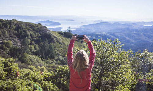 Rear view of person photographing on mountain