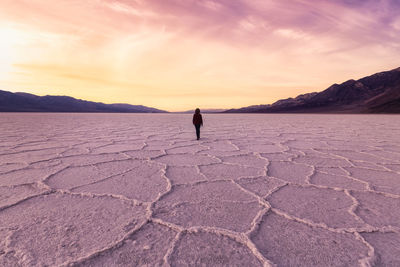 Full length of man standing on shore against sunset sky