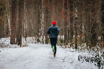 Male runner running trail in winter snowy forest