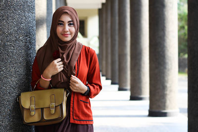 Portrait of young woman standing against wall