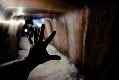 Cropped hand of person gesturing in illuminated tunnel