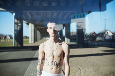 Full length of shirtless man standing in front of building