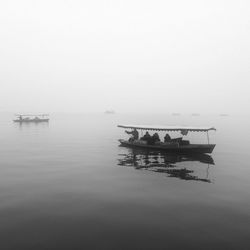 Boats in calm lake against sky