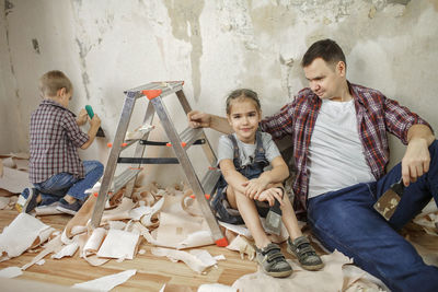 Full length of father and son sitting on floor