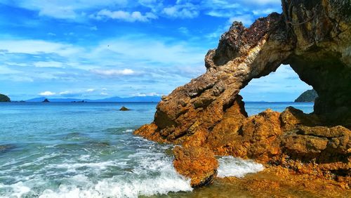 Rock formation on sea shore against sky