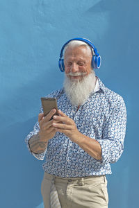 Young man using mobile phone against blue sky