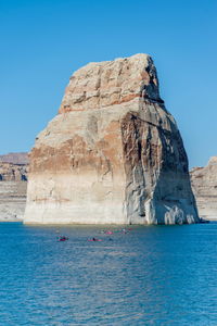 Rock formations in sea against clear blue sky