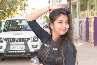 Portrait of happy young woman standing in car