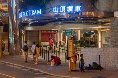 People walking on illuminated store in city