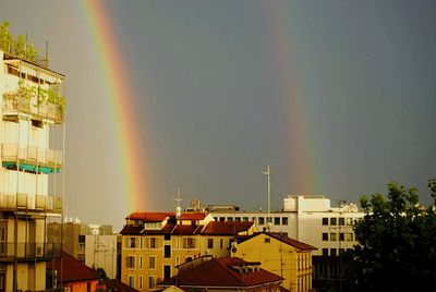 Rainbow over city against sky