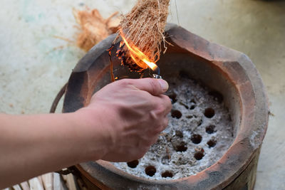 High angle view of person preparing burning coconut peel on charcoal stove