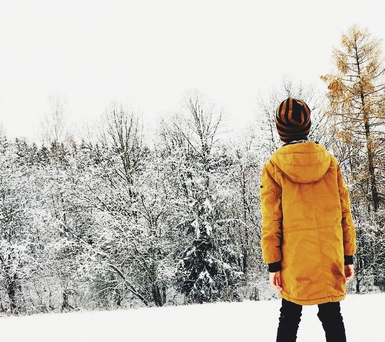 REAR VIEW OF PERSON STANDING ON SNOW COVERED LAND