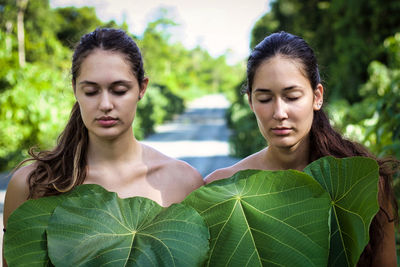 Shirtless friends with eyes closed and leaves on road