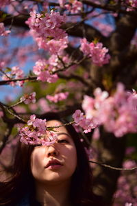 Portrait of beautiful woman with pink flowers against blurred background