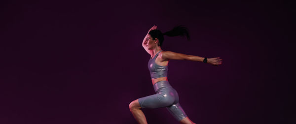 Full length of woman exercising against black background