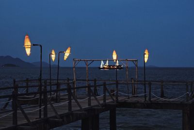 Illuminated street light on beach against clear sky