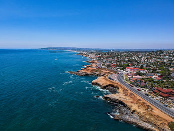 High angle view of sea and buildings against blue sky