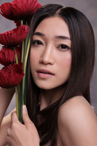 Close-up of young woman with red flower