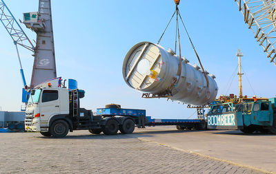 Vehicles on pier against clear blue sky