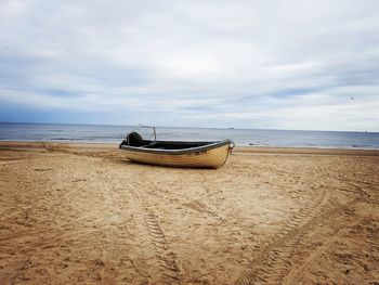 Boat moored on beach against sky