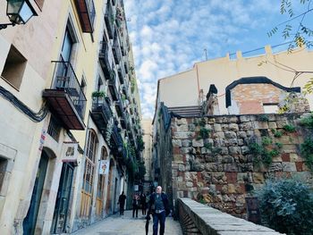 People walking on footpath amidst buildings in city