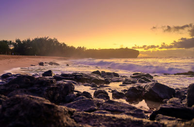 Rocks on shore against sky during sunset