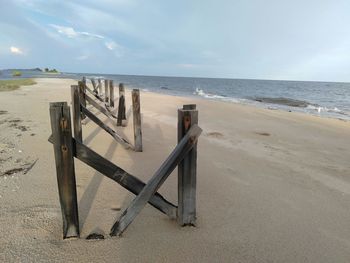 Wooden posts on beach against sky