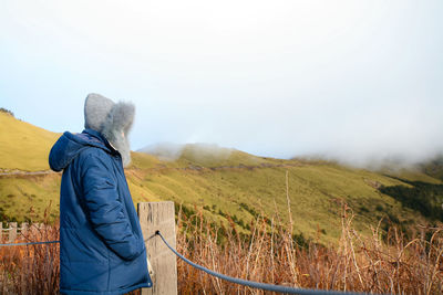 Woman standing by railing and plants during winter