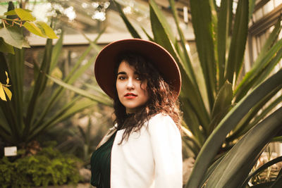 Portrait of beautiful young woman standing against plants