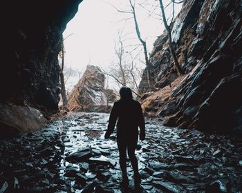 Rear view of woman standing in cave