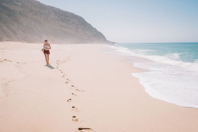 Woman walking on beach against clear sky