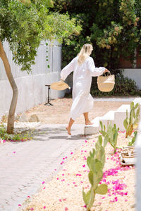 Woman wearing white dress running towards her house