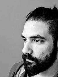 Close-up of thoughtful young bearded man looking away against gray background