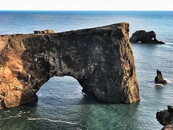 Rock formation by sea against clear sky