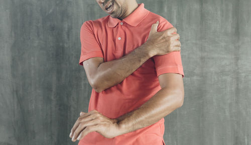 Midsection of man holding red while standing against wall