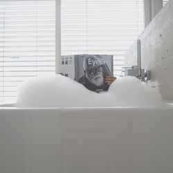 Woman holding magazine in bathtub at home