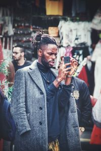 Young man using mobile phone while standing on street