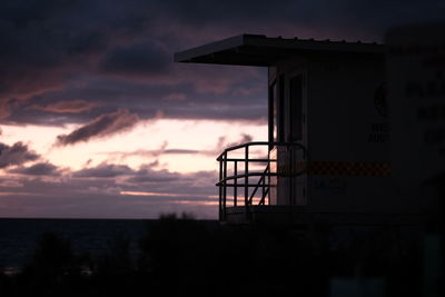 Silhouette built structure by sea against sky at sunset