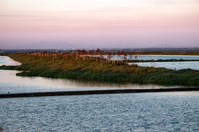 Scenic view of river against sky at sunset