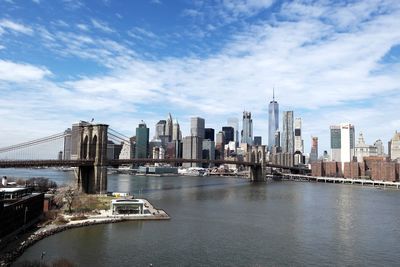 Bridge over river by buildings against sky in city