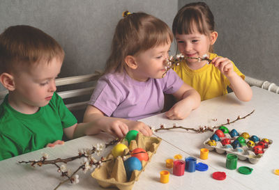 Children paint eggs. children sit at a table with painted easter eggs and talk. 