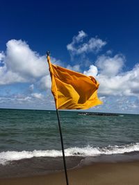Yellow flag on beach against sky